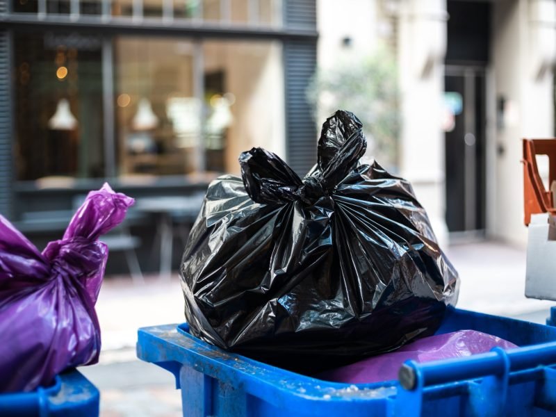 And black bags of trash on a garbage bin during daytime